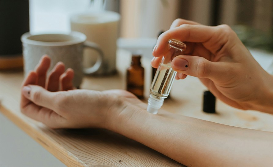 En person duttar en flaska med olja mot sin underarm. En person duttar en flaska med olja mot sin underarm.