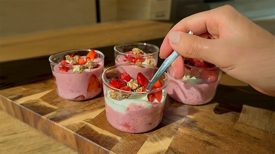 Fyra stycken glas med chiapudding med Healthwell Super Fruits p� en tr�bricka som st�r p� en k�ksb�nk.
