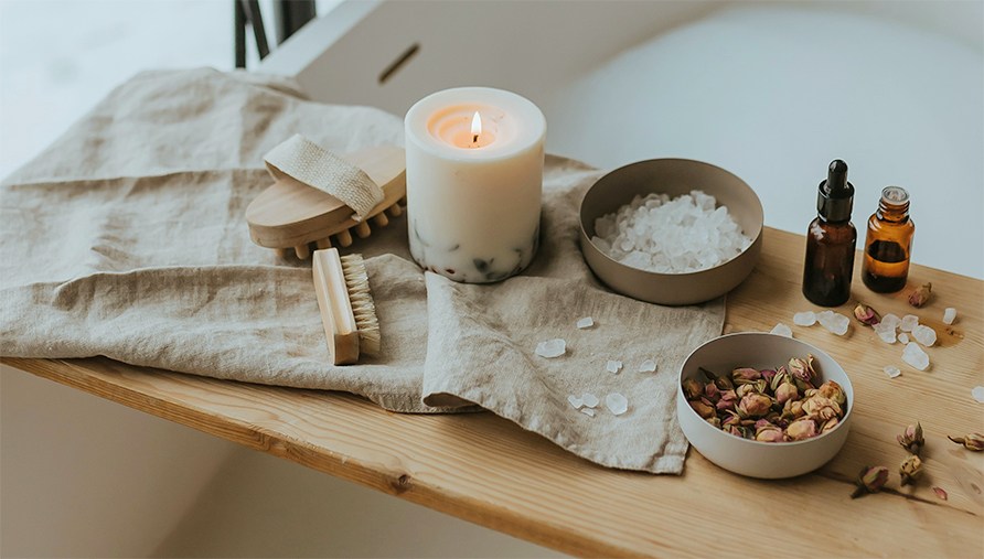 En bricka över ett badkar med scrub, badsalt och eteriska oljor. En bricka över ett badkar med scrub, badsalt och eteriska oljor.