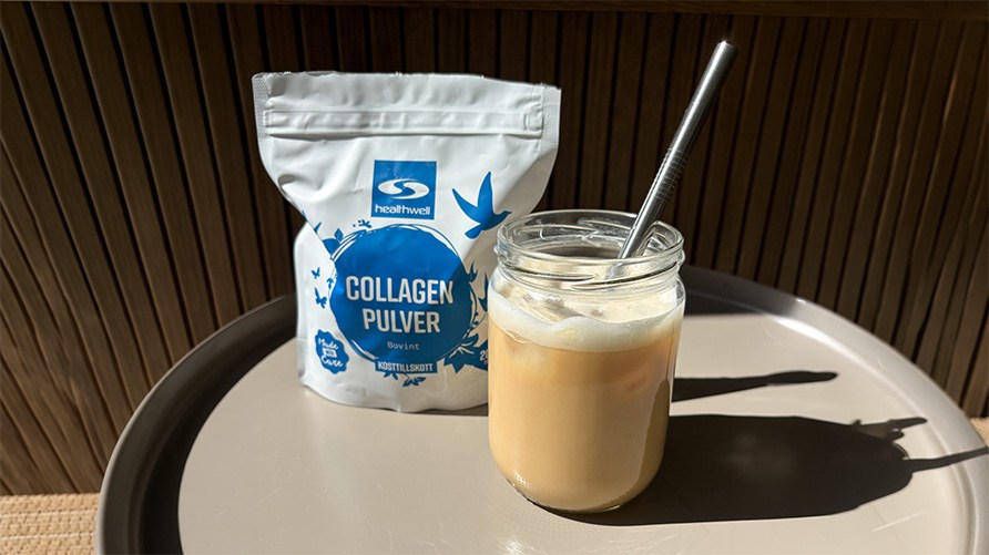 Ett glas med islatte st�r p� ett bord utomhus tillsammans med en p�se Healthwell Collagen Pulver Bovint.