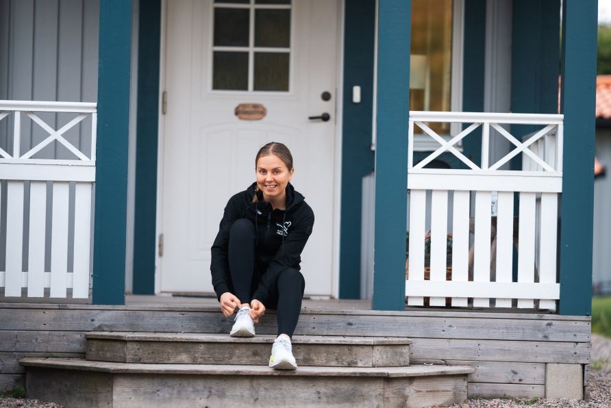 Svensk Hlsokosts ambassadr Josefine Johnsson sitter p en trappa p en veranda och snrar p sig sina lparskor.