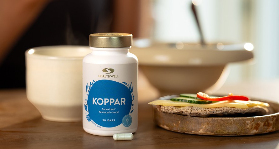 En burk Healthwell Koppar på ett frukostbord med en smörgås och en kopp te.