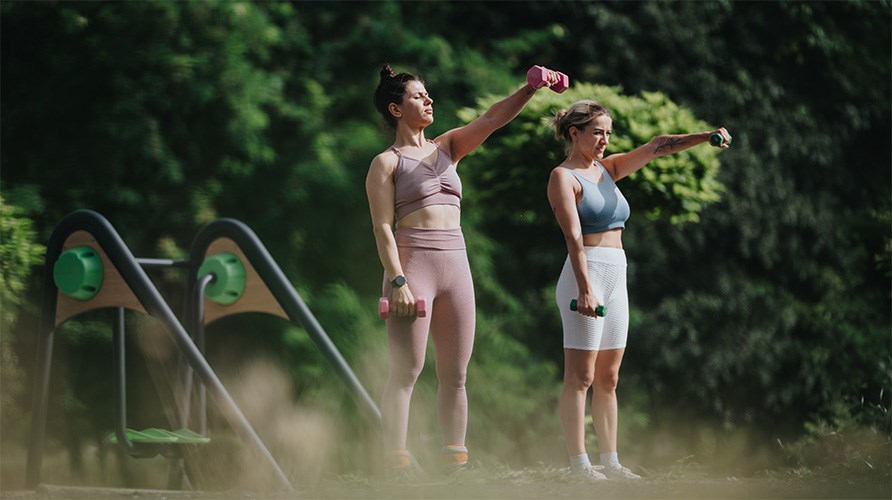 Tv� kvinnor tr�nar utomhus en gr�nskande sommardag.