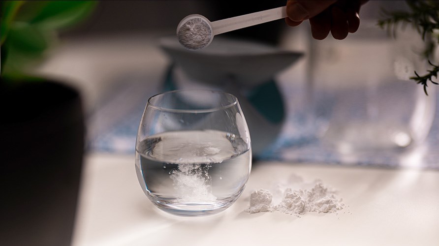 Kreatinpulver blandas i ett glas med vatten
