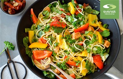 En stekpanna med pasta, kyckling och grönsaker.