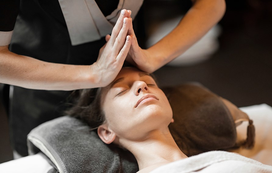 Kvinna blundar och njuter av en lymfmassage i ansiktet.