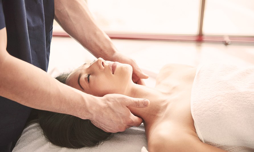 Kvinna f�r en mjuk lymfmassage kring nackomr�det, liggande p� en massagebrits.