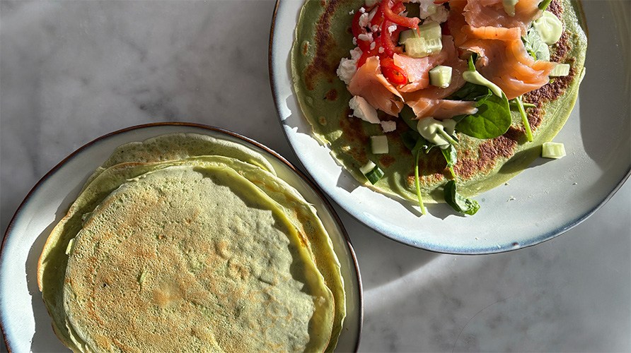 Matiga pannkakor med spirulina och moringa p� tv� tallrikar tillsammans med gravad lax, gr�nsaker och fetaost. 