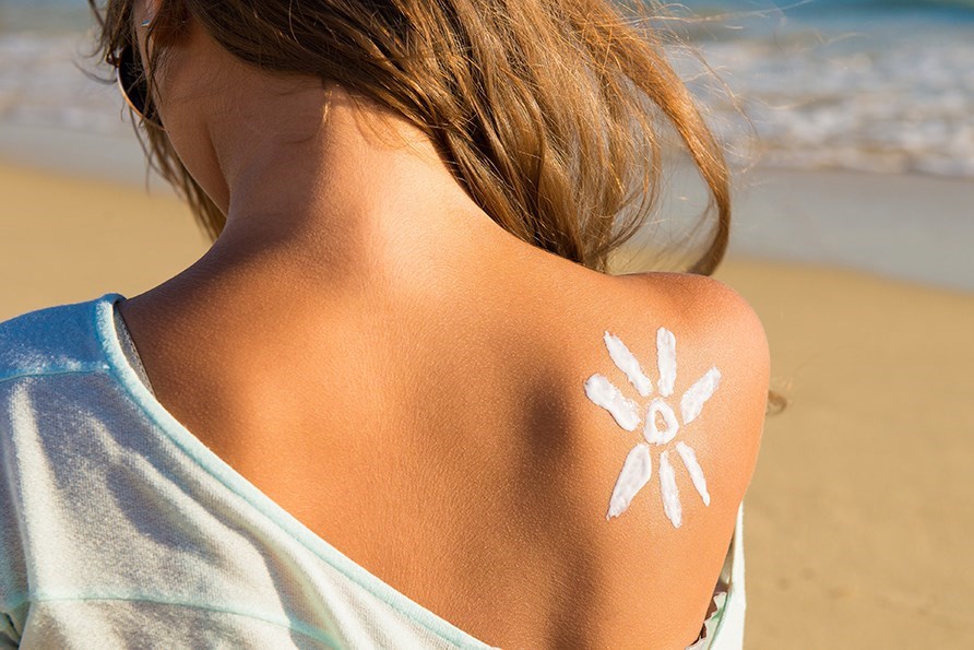 En tjej har en sol ritad med solkräm på axeln.
