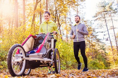 Kvinna och man motionerar med barnvagn