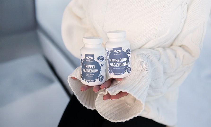 Kvinna sitter och h�ller i tv� burkar med magnesiumtillskott