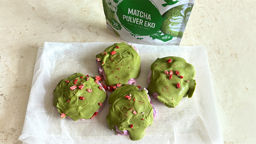 Frysta yoghurttoppar med bl�b�r och matcha p� en k�ksb�nk tillsammans med en p�se Healthwell Matcha Pulver EKO